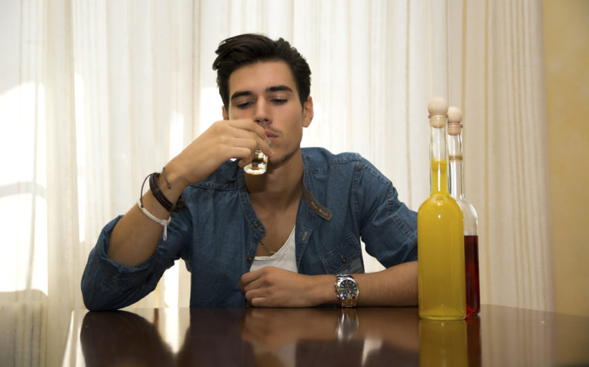Young man sitting drinking alone at a table with two bottles of