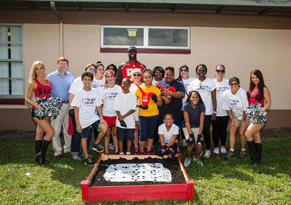 Florida elementary school students pose with Tampa Bay Buccaneers cheerleaders and players as they launch a school garden. (Source: Courtney Johnson/UnitedHealthcare)