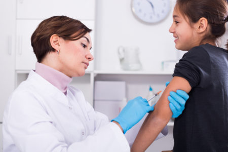 Doctor providing flu vaccine shot to Latina girl