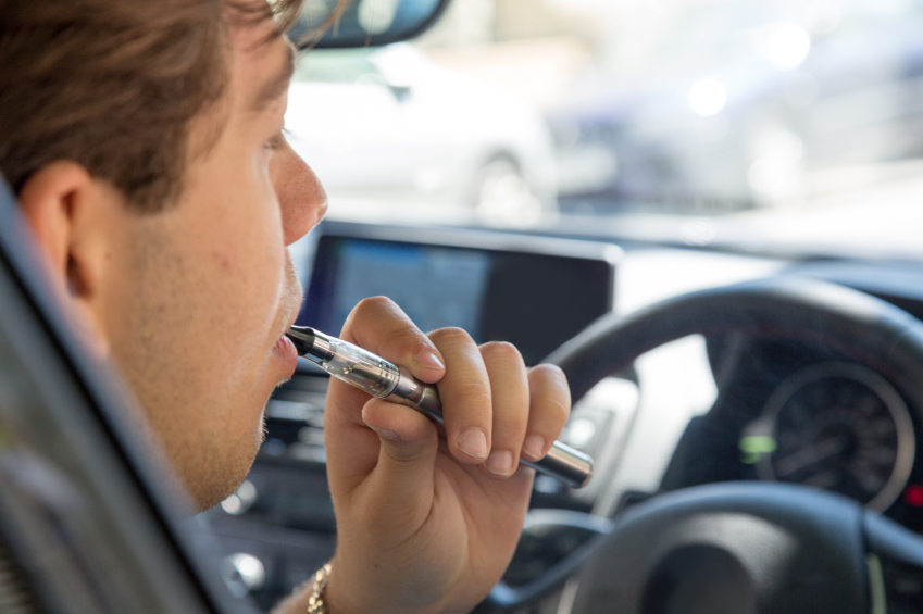 Man smoking an e-cigarette as he drives a car