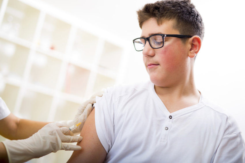 Teenage boy getting vaccination shot flu in his arm