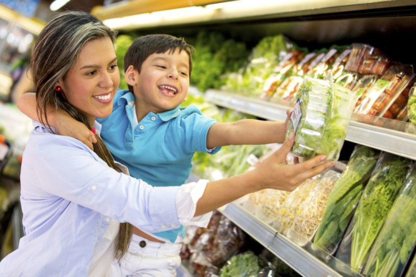 latina mom in grocery store with fruits and vegetables