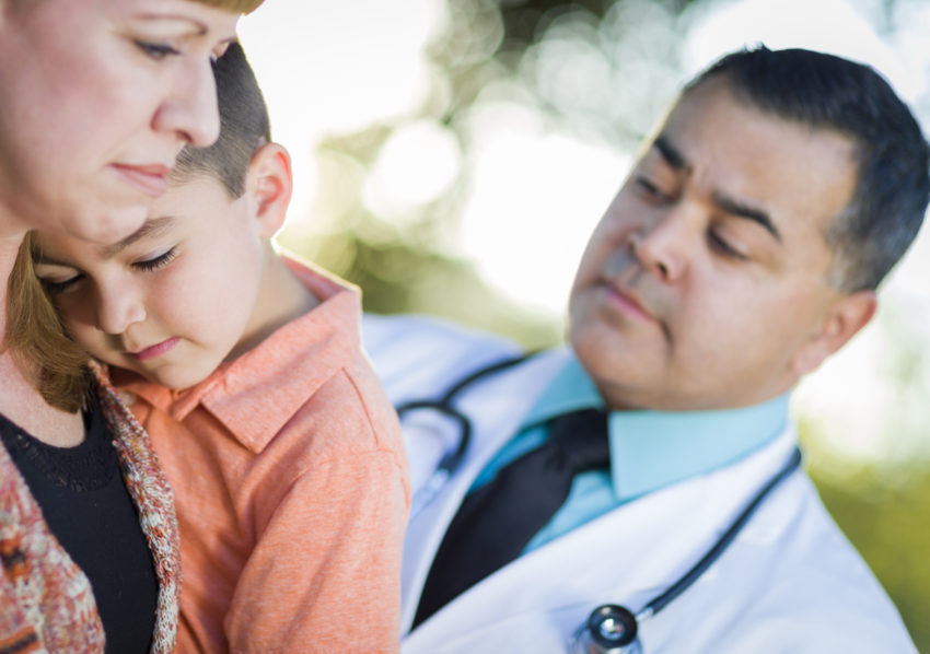 sad latino boy with mom and doctor