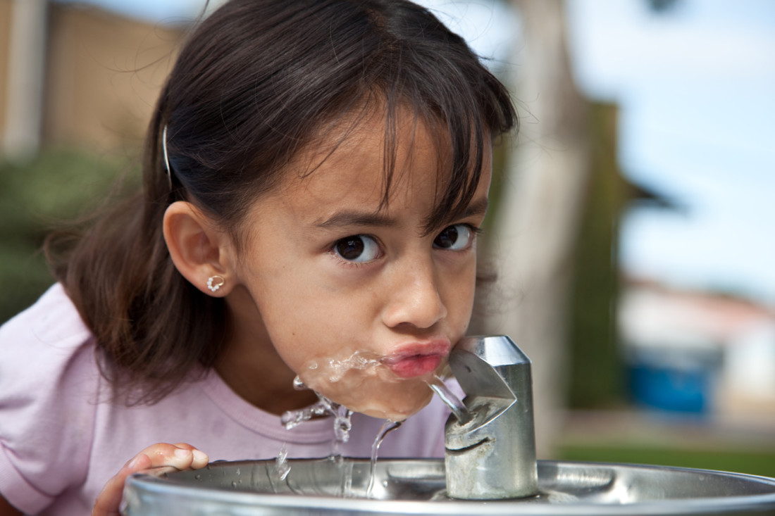 latina girl drinking from water fountain