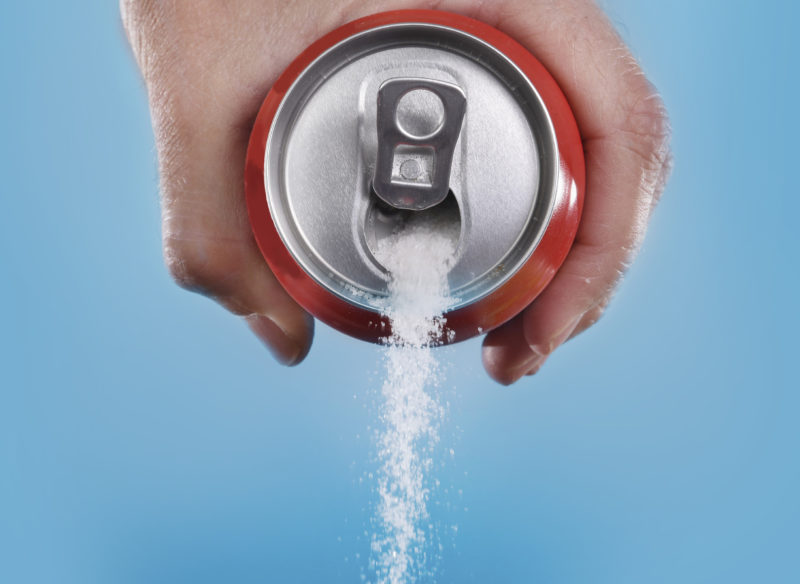 hand holding soda can pouring a crazy amount of sugar in metaphor of sugar content of a refresh drink