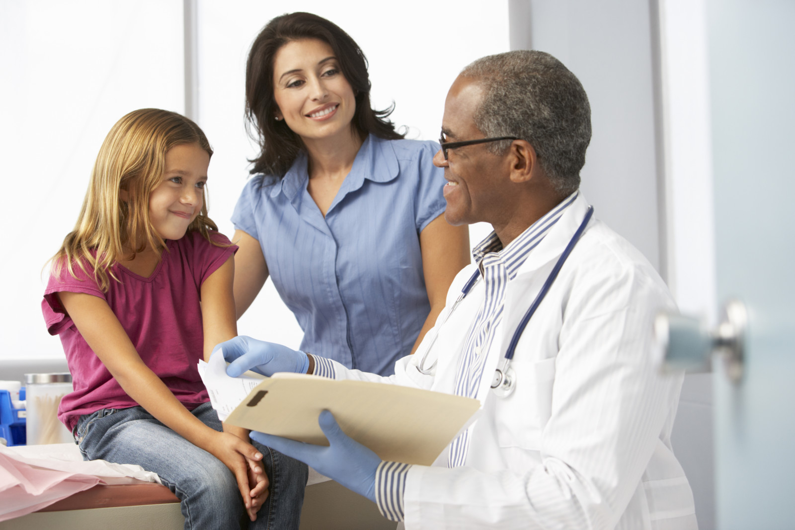 Doctor In Surgery Examining Young Girl with Latina Mom
