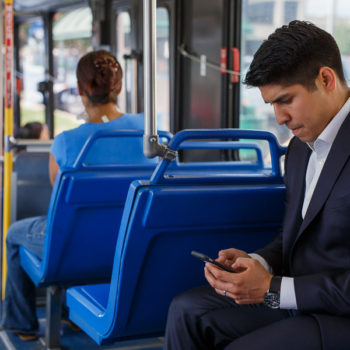 Councilmember Rey Saldaña checks his phone to locate his current route on the bus Source Scott Ball Rivard Report