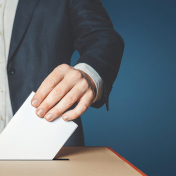 voter putting ballot in voting box
