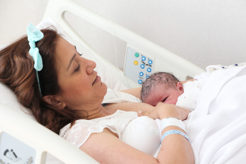Mother breastfeeding her baby in hospital room