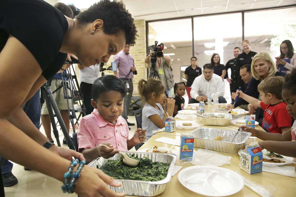 Instructional specialist helps student serve himself greens as Pre K 4 SA announced partnership with the Food Bank s Source Tom Reel Express News