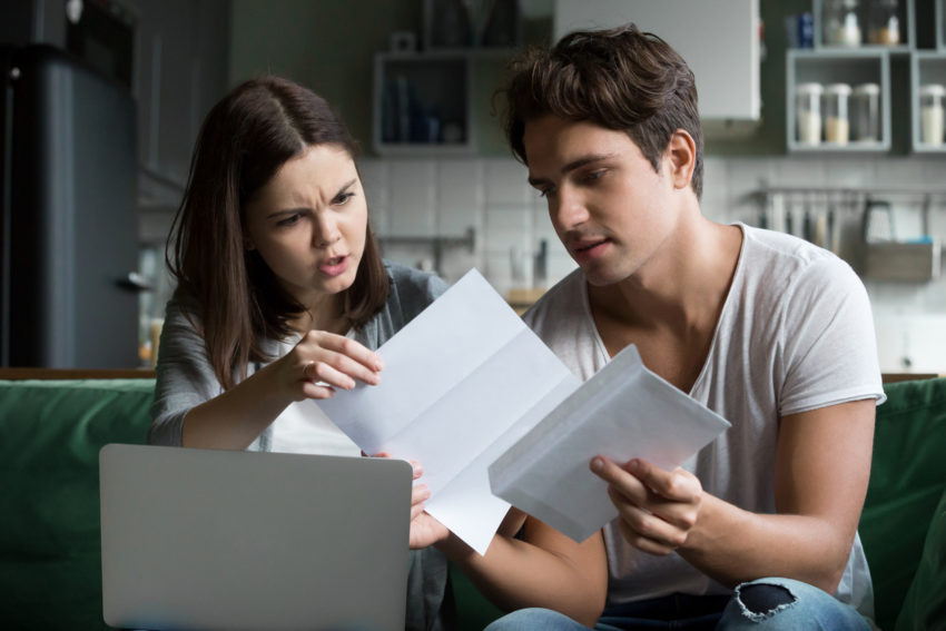 Frustrated wife shocked by bad news reading letter with husband, housing affordable