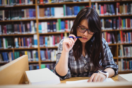 Latino Hispanic college student studying in a university library