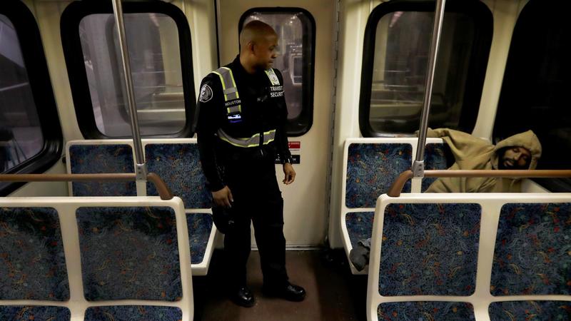 A Metro transit security guard wakes up a sleeping person on the Red Line. (Francine Orr / Los Angeles Times)