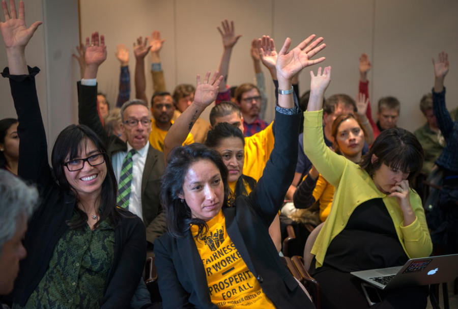 Marcela Diaz, center, director of Somos Un Pueblo Unido, and others raise their hands in support of a bill that would raise the states minimum wage Eddie MooreAlbuque.jpg