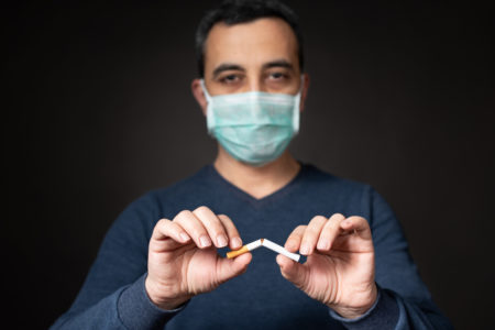 smoking & coronavirus man with mask quits smoking cigarettes amid covid-19