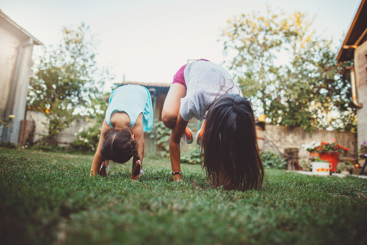 two girls doing hand stand in yard physical activity to fight obesity
