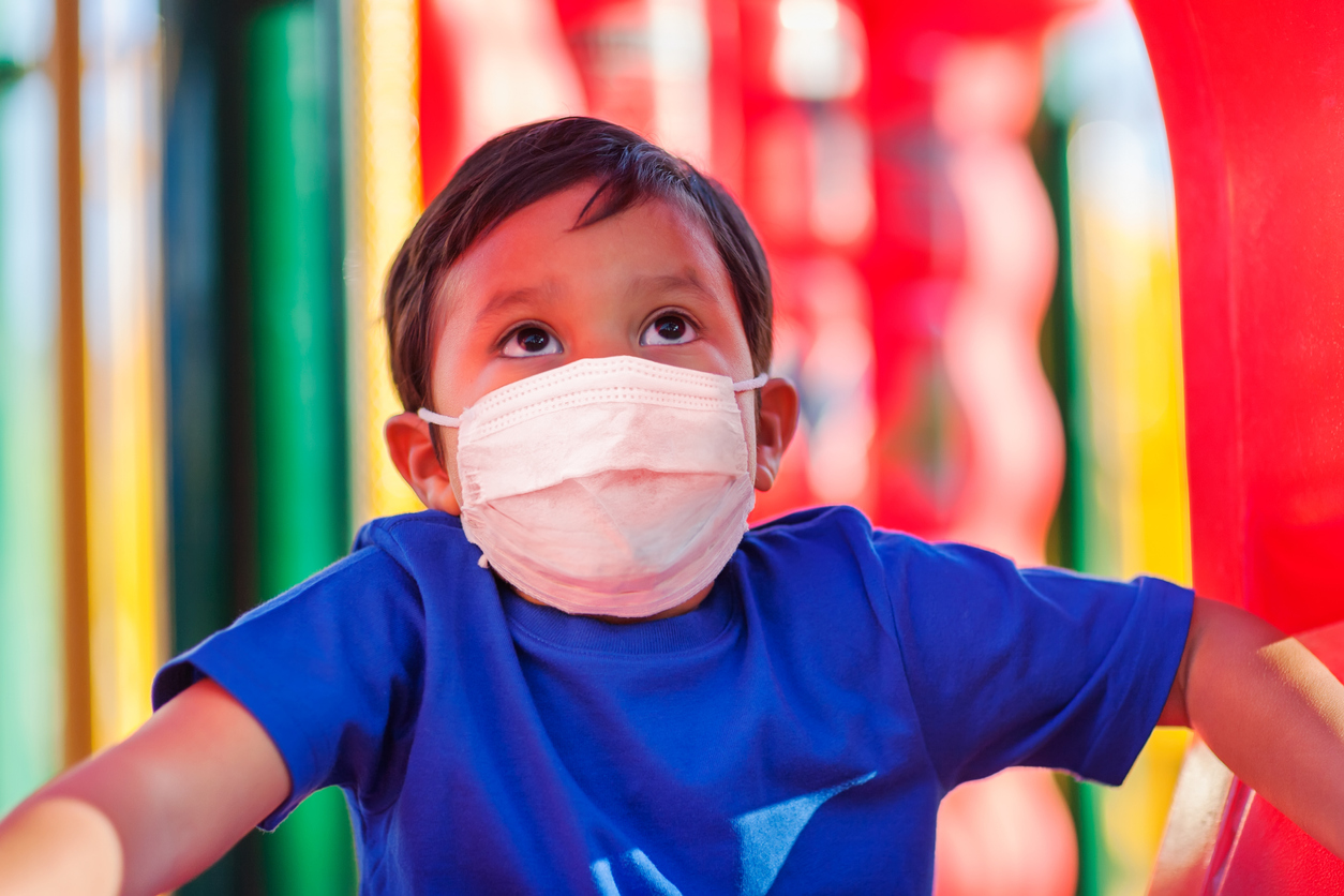 latino child on playground with face mask to prevent covid-19 coronavirus