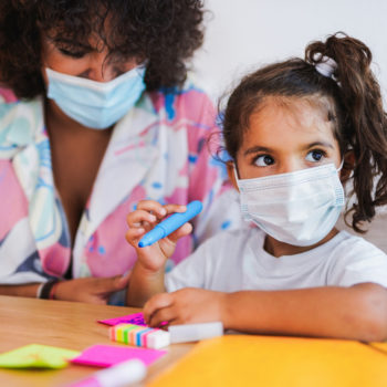 hispanic latino child girl student home coloring work wearing face mask amid COVID-19 coronavirus