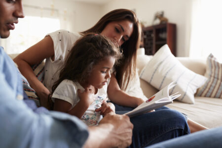 Latino parents reading with child. 