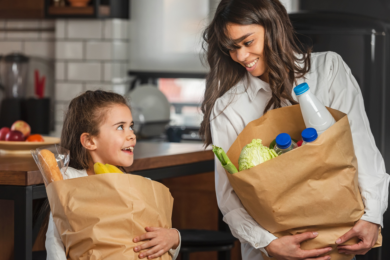 cheerful-little-daughter-helping-the-mother-to-carry-groceries-from-the