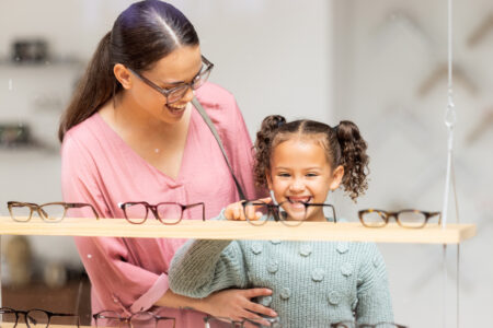 Decision, glasses and girl with her mother at the optometrist for vision and check on eyes together. Customer, medical and child shopping for eyeglasses with her mom at the ophthalmologist clinic