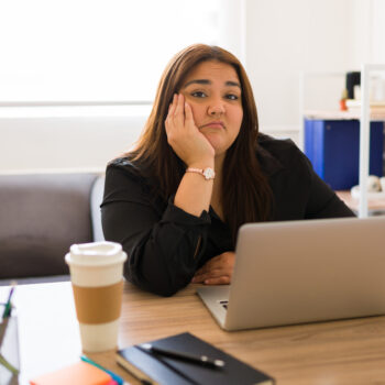 Bored woman working as a manager in a business making eye contact while annoyed and tired in her office desk