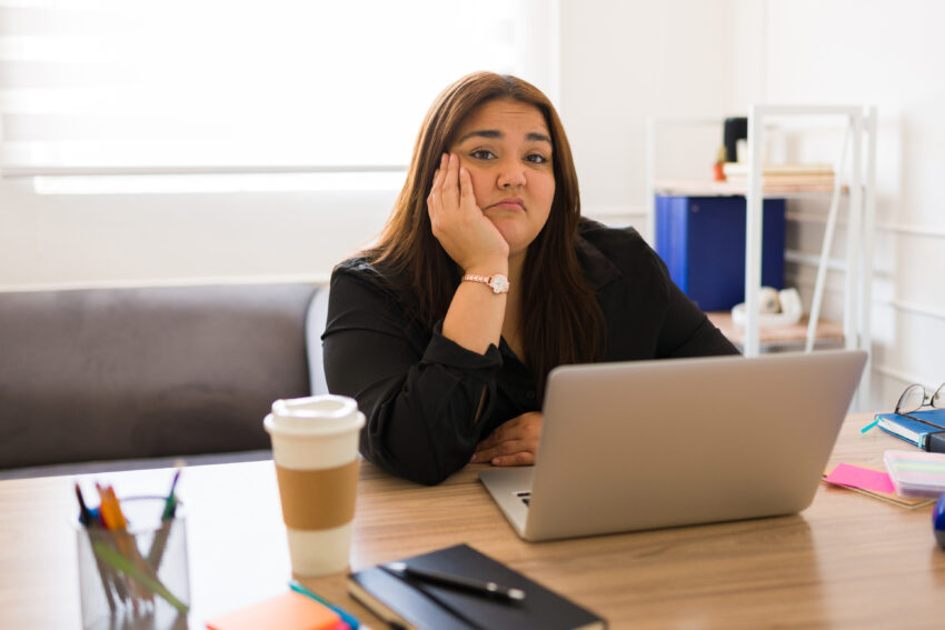 Bored woman working as a manager in a business making eye contact while annoyed and tired in her office desk