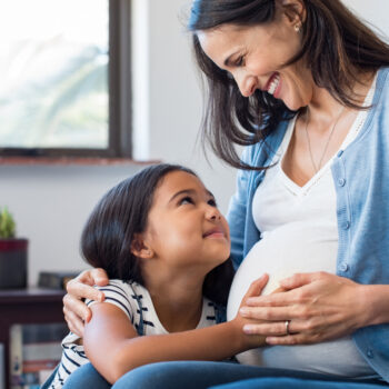 Daughter touching the belly of her pregnant mother