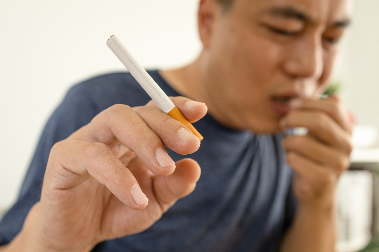 Male smoker holding a cigarette suffering from chronic cough