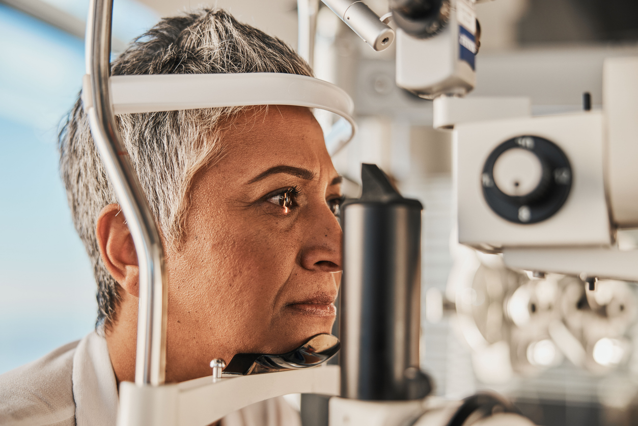 Optometry, slit lamp and eye exam by senior woman or patient with medical insurance using machine. Ophthalmology, eyesight and female test vision in clinic as eyecare during consultation