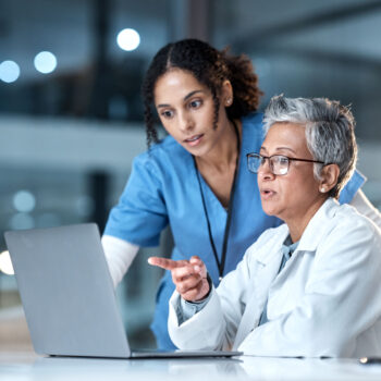 Healthcare professionals viewing information on laptop.