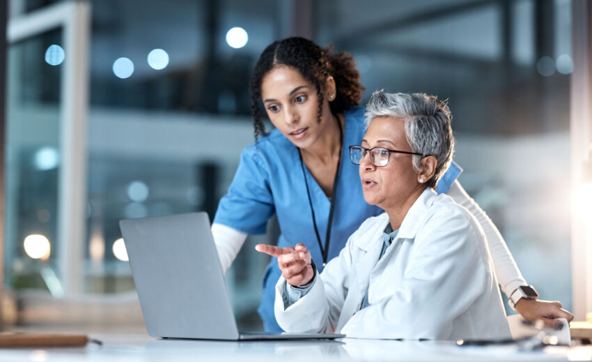 Healthcare professionals viewing information on laptop.