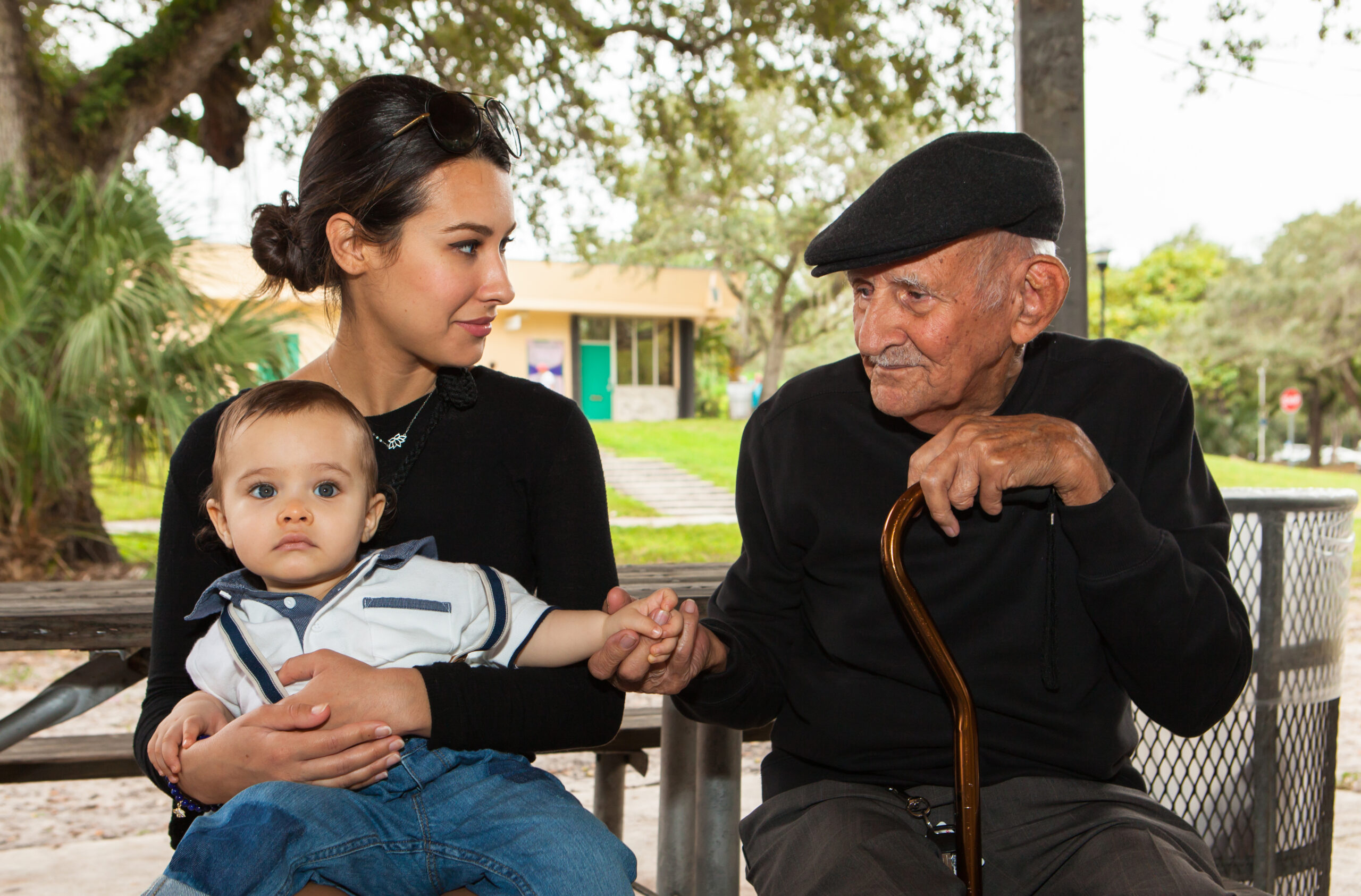 Elderly eighty plus year old man with granddaughter and great grandson in a outdoor park setting.