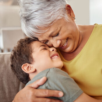 Child and grandma hug and bond in living room together