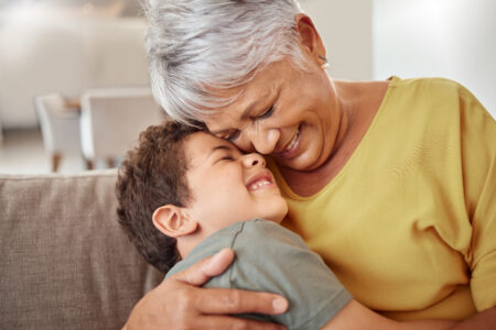 Child and grandma hug and bond in living room together
