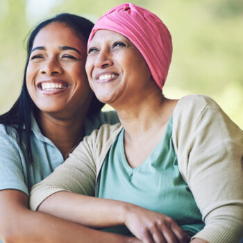 Happy, sweet and sick mature female person embracing her adult daughter with a smile in outdoor garden.
