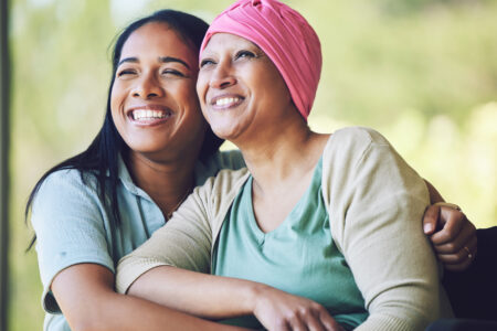 Happy, sweet and sick mature female person embracing her adult daughter with a smile in outdoor garden.