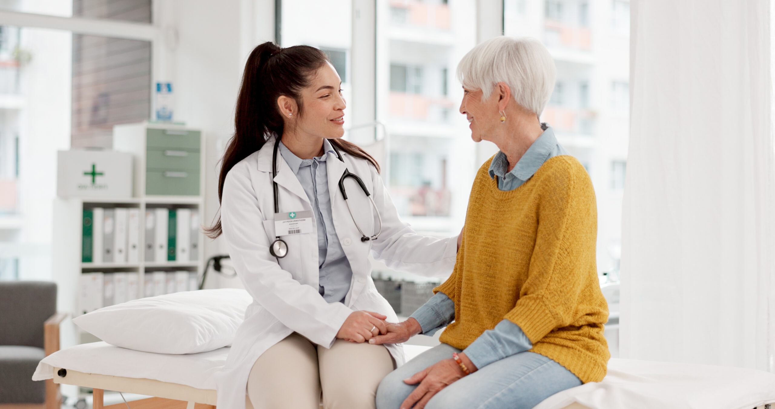 Holding hands, happy or doctor with patient in consultation for healthcare advice or checkup at hospital. 