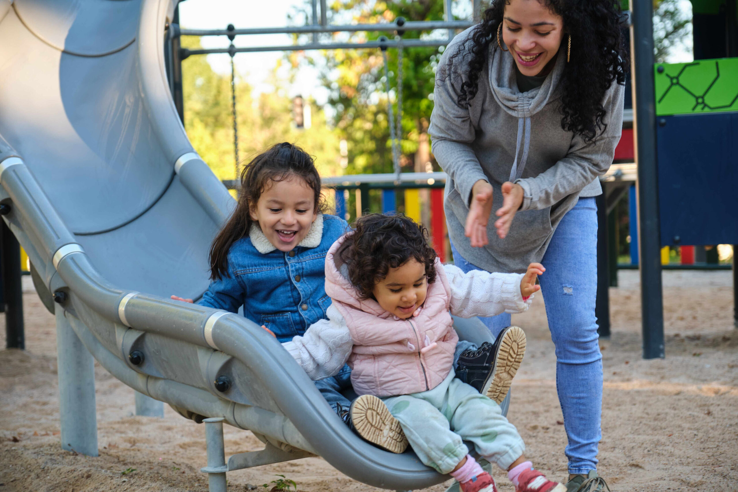 mother playing with her children at the slide in a park