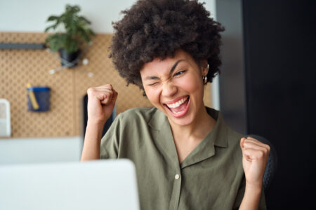 Young woman winner looking at laptop computer. Excited euphoric girl student celebrating good exam result, university admission, internet victory success winning online.
