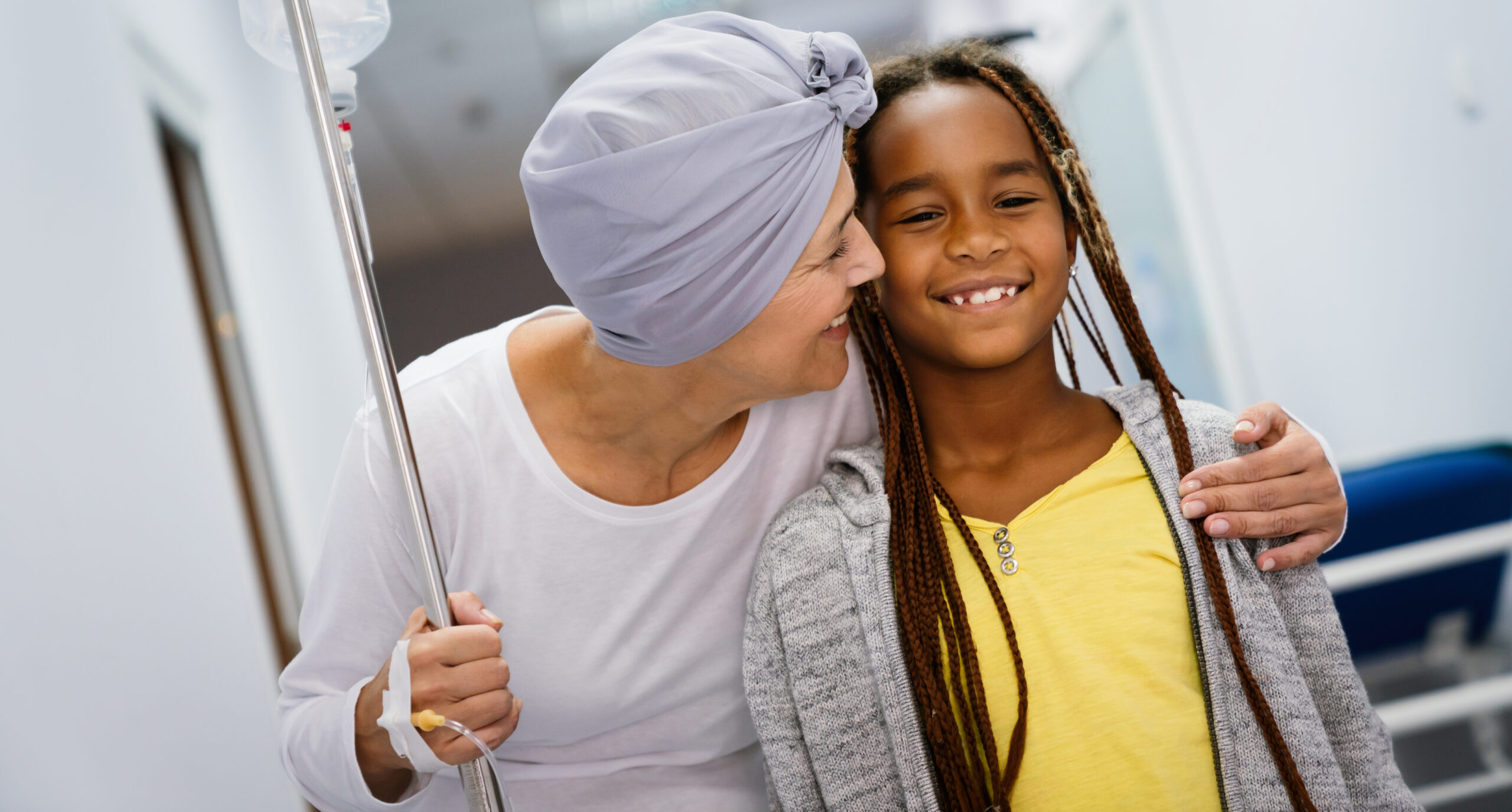 Sick senior woman with cancer hugging her young child in hospital. Family support concept.