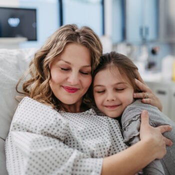 Daughter visiting mother in hospital after successful surgery, hugging her. Emotional support from family for patients in hospital.