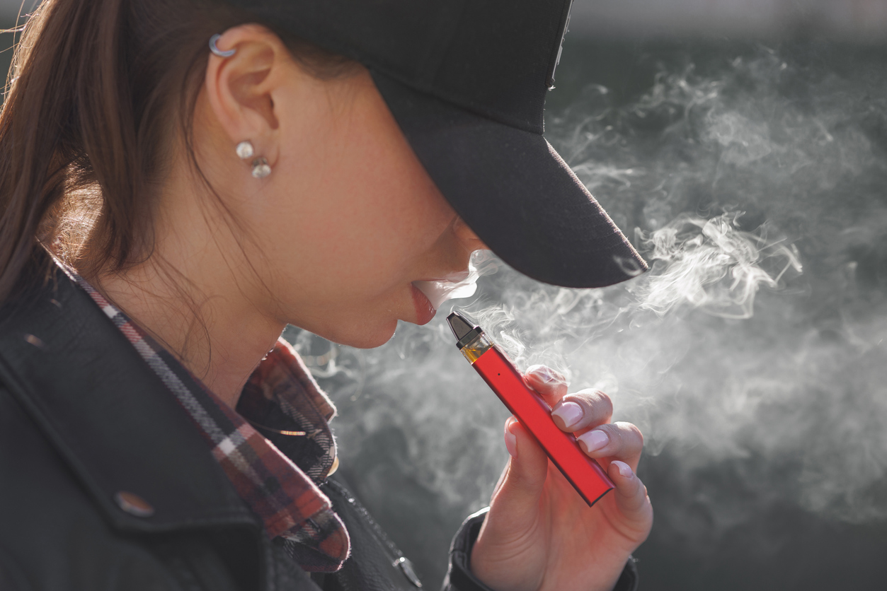young girl smokes a vape close-up on a dark background, women smoke electronic cigarett