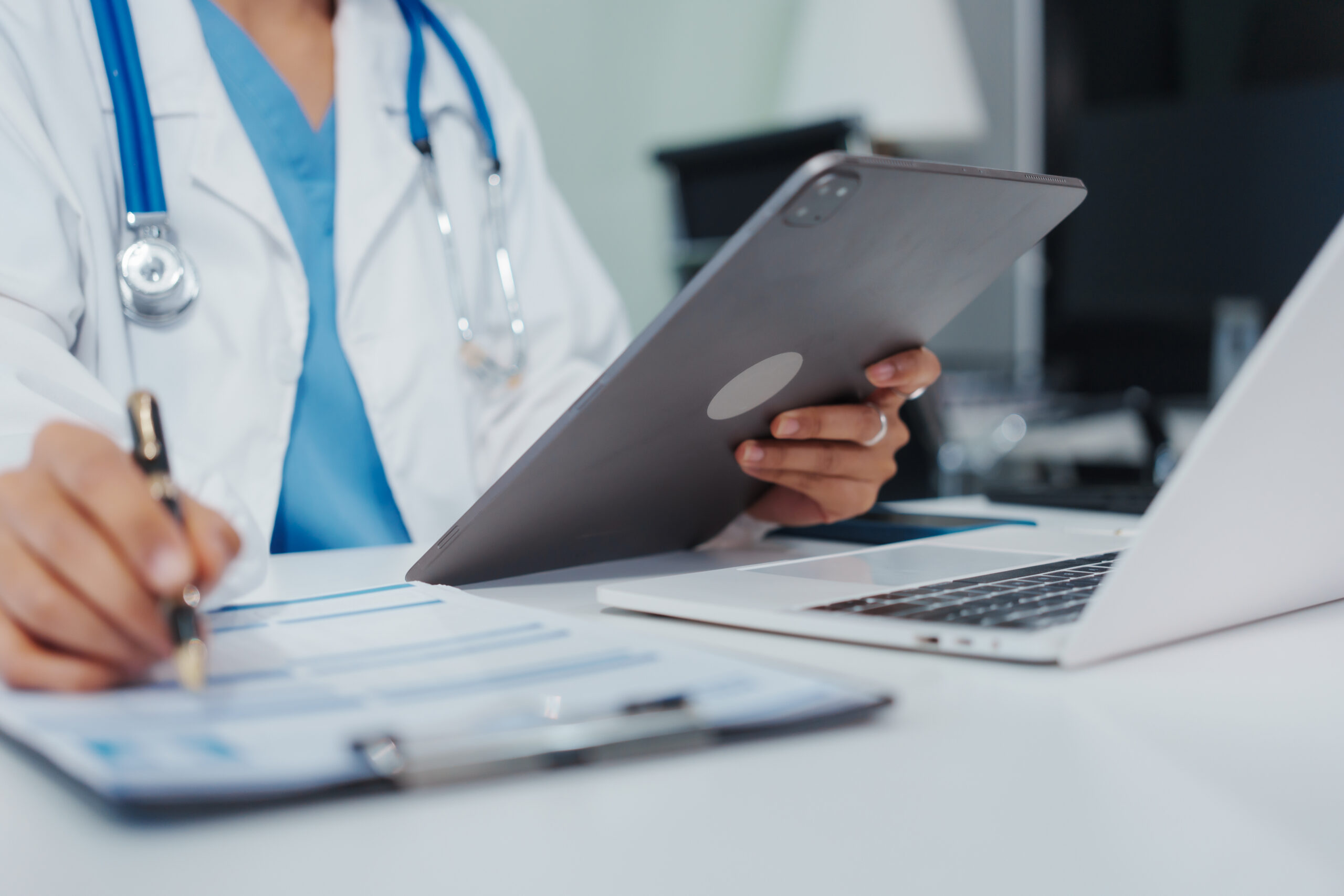 Female doctor is reviewing medical records, working on a computer, planning treatment, giving online consultations, and explaining medications to patients via a medical video call in a clinic