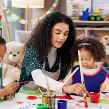 Childcare teacher helping students with activity.