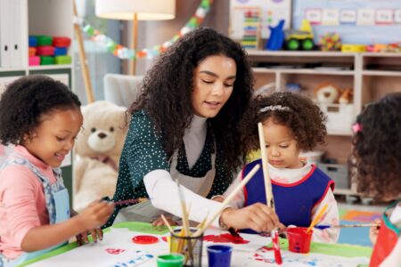 Childcare teacher helping students with activity.