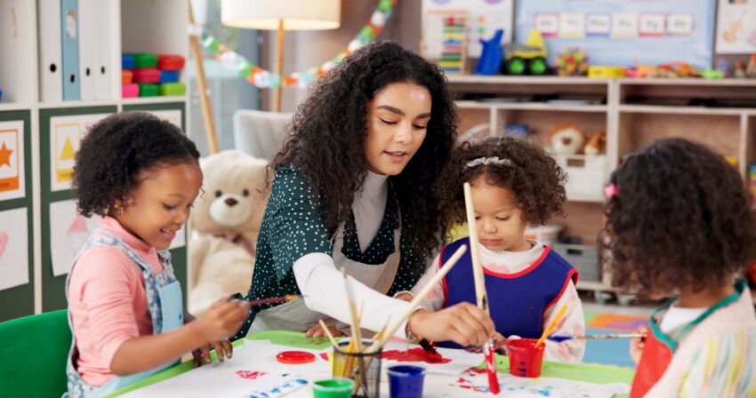 Childcare teacher helping students with activity.