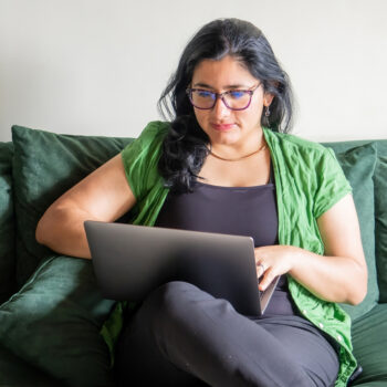Woman using laptop and sitting on couch