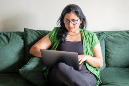 Woman using laptop and sitting on couch