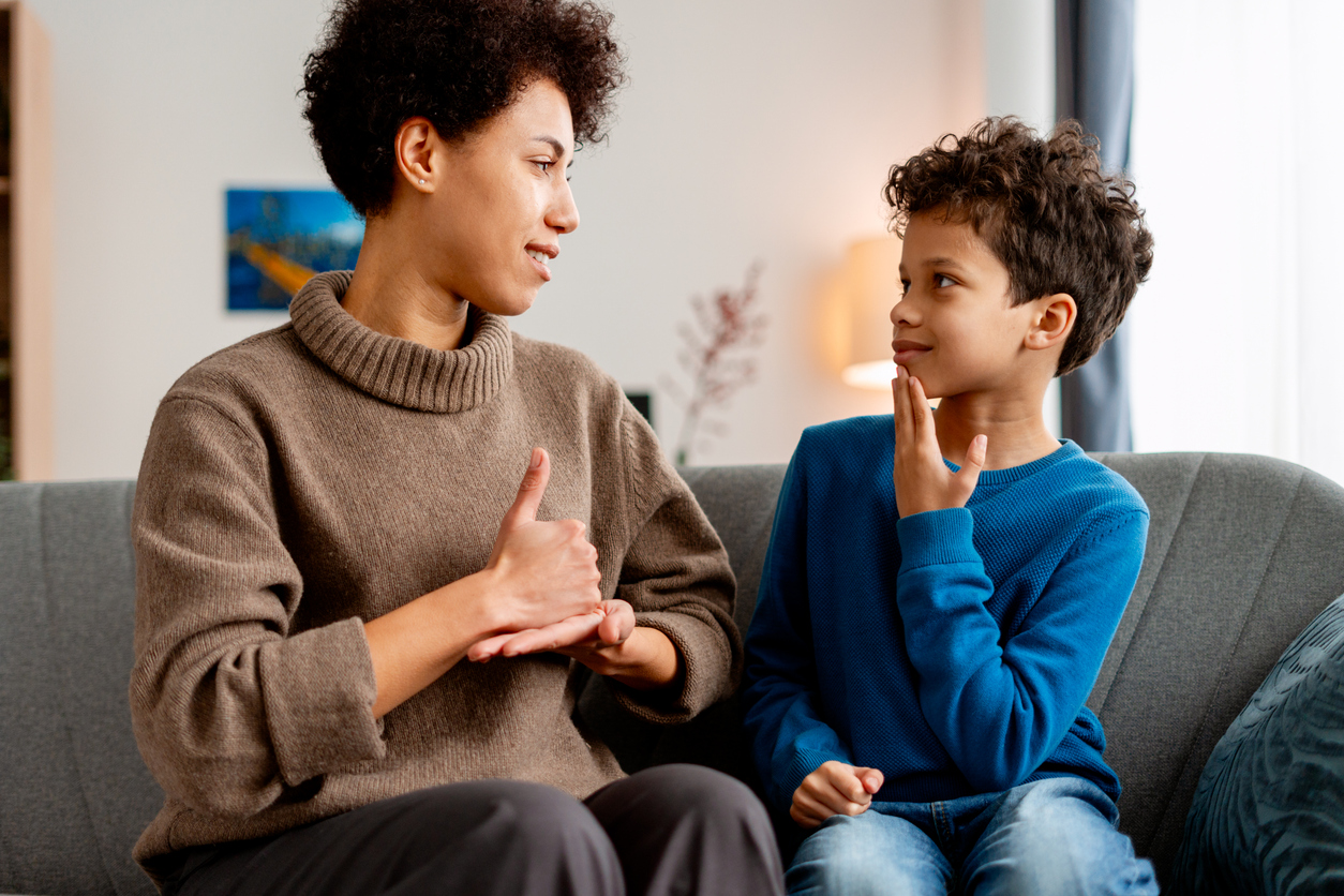 Mother teaching son sign language at home, fostering communication